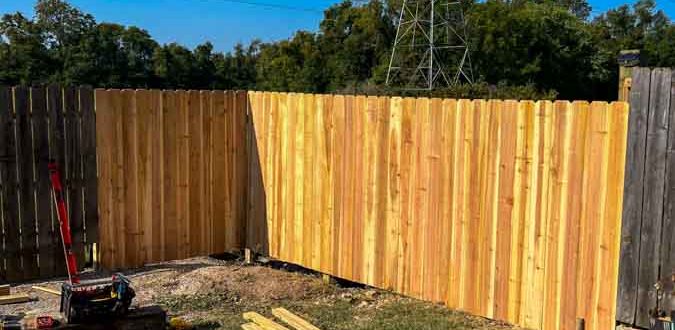 Image showing a new wooden privacy fence construction process in a backyard with tools and materials on the grass, representing home repair and deck services.