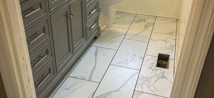 Sleek bathroom interior with gray vanity, marble floor tiles, and classic white bathtub, showcasing modern bathroom remodeling.